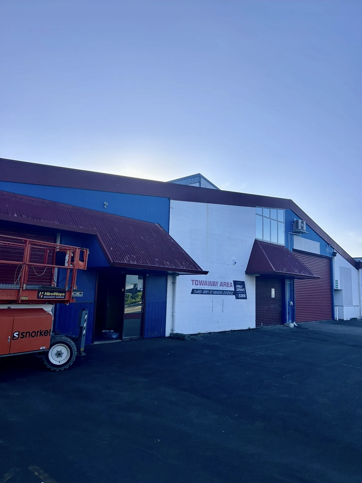 Commercial building before repainting, with blue and white walls and burgundy awnings