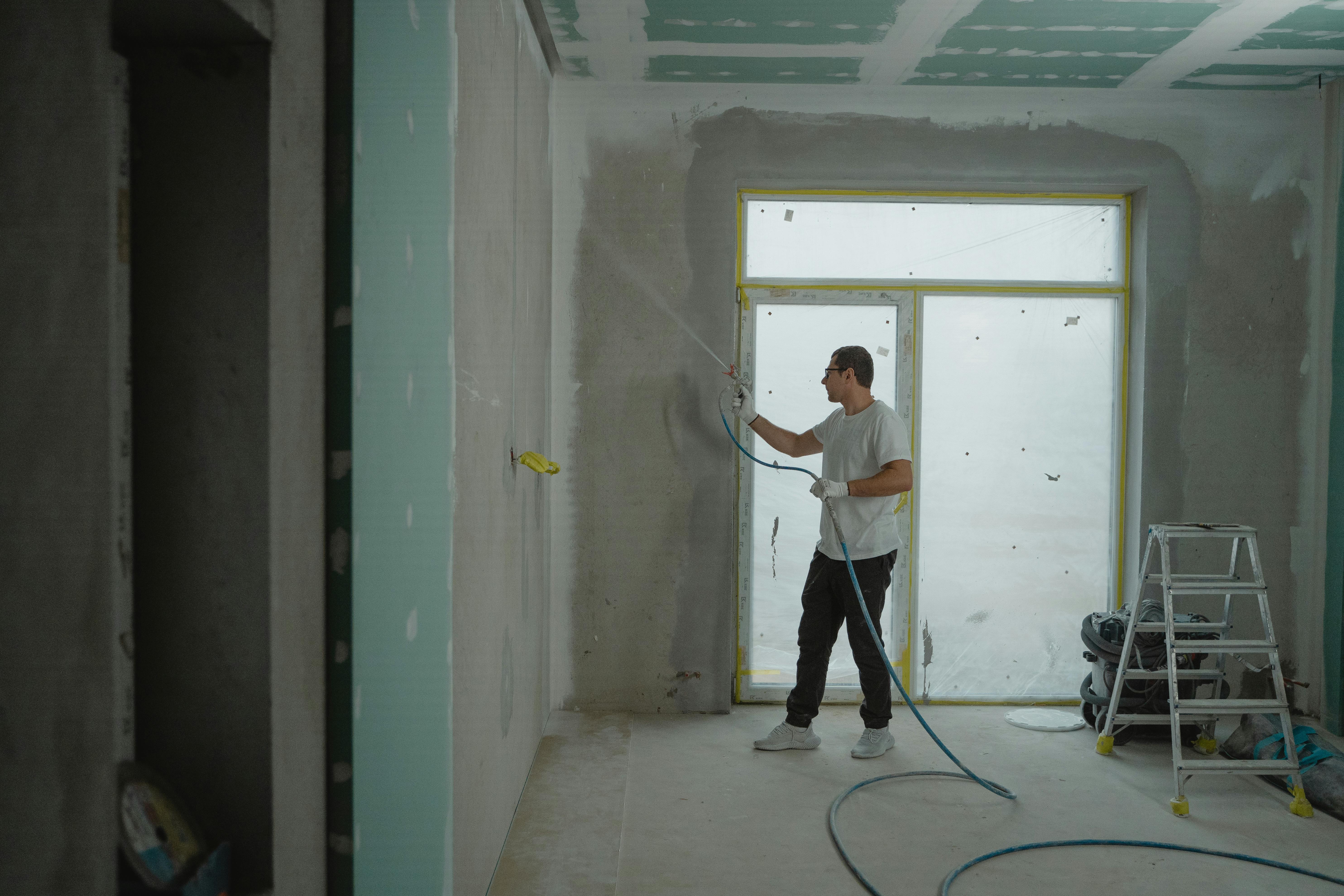 portrait painter using an airless spray gun on a wall